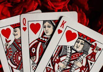 Photo of the Jack, Queen and King of hearts playing cards placed on a red plush background for article titled How Aggregators Expand Table-Game Choices for Card Fans